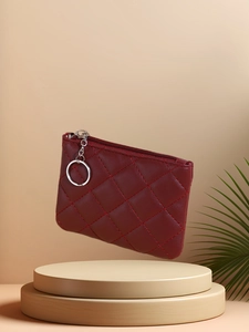 Detailed close-up of a red quilted leather mini coin purse with silver zipper and keyring