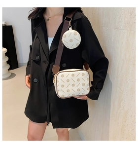 Detail view of cream crossbody bag with monogram print and detachable round coin purse