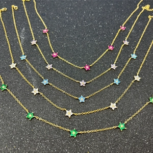 Detail of gold floral pendants with colorful inlaid crystals on a dark textured background