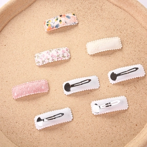 Set of 6 square BB clips with sweet floral embroidery and lace on a cork tray