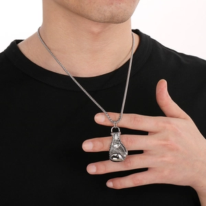 Gros plan d'un pendentif gant de boxe vintage en acier pour homme porté avec chaîne argent