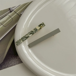 Detail of green marble and solid sage acetate hair clips on a white display plate