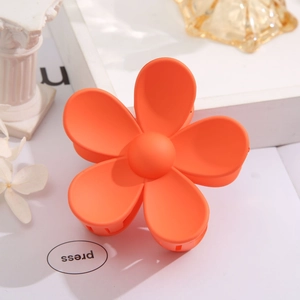Detail of an orange matte flower hair claw clip on a minimalist elegant background