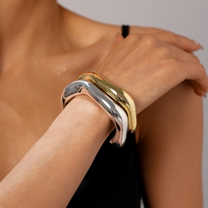 Bracciali rigidi a onde irregolari minimalisti in finitura oro e argento su modella