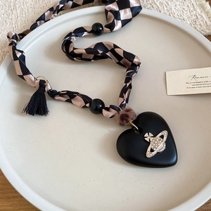 Detail of matte heart pendant with Saturn ring logo on checkerboard silk scarf necklace