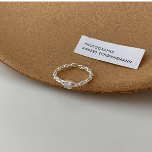 Close-up of a silver Cuban link ring featuring a square-cut clear zircon stone setting