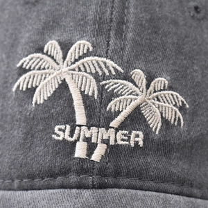 Close-up of summer palm tree embroidery on a washed dark grey cotton baseball cap