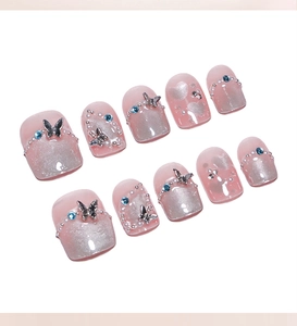 Macro detail of French cat eye press-on nails with 3D metal butterflies and rhinestones