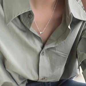 Close-up of a polished heart pendant necklace worn on the collarbone for styling