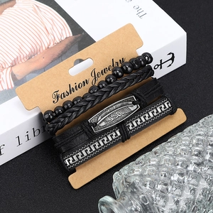 Détail d'un ensemble de 4 bracelets en cuir noir tressé avec un pendentif plume en métal