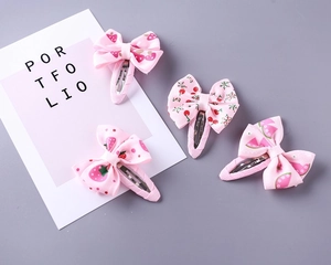 Close-up of 4-piece pink ribbon hair clips featuring strawberry and watermelon patterns