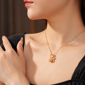 Dettaglio della collana dorata con ciondolo a sfera cava e croce con micro-pavé di diamanti