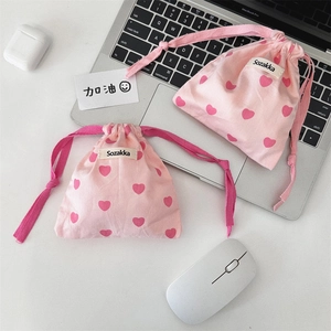 Detailed macro view of pink heart patterned drawstring storage bags on a desk