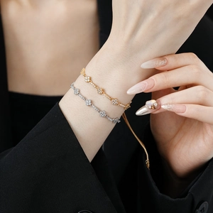 Adjustable zircon clover bracelet in gold and silver finish on a model's wrist