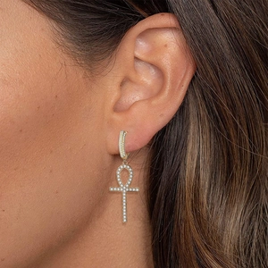 Gold-plated Ankh cross earrings with white zircon stones shown on a model