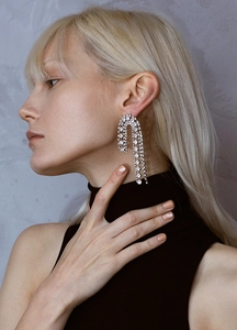 Close-up of sparkling rhinestone tassel earrings worn by a model in a fashion style