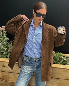 Close-up of brown suede oversized blazer paired with a striped shirt and blue jeans