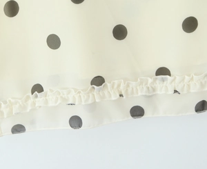 Close-up of beige polka dot fabric with ruffles and high-quality stitching details