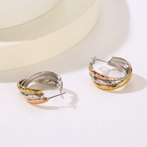 Detail of three-tone interlocking hoop earrings with engraved floral patterns in steel