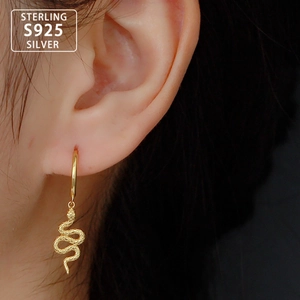 Unique gold S925 sterling silver snake hoop earrings worn by a model in soft light