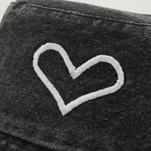 Black denim bucket hat featuring white heart embroidery detail and premium twill texture