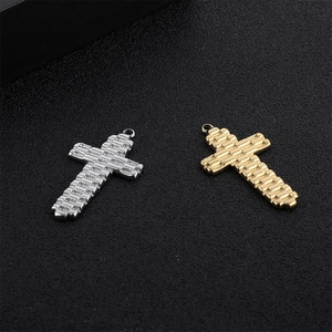 Détail des pendentifs croix en acier inoxydable argent et or avec des textures maillées