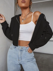 Detail of a black cropped zip-up hoodie paired with a white tank top and blue jeans