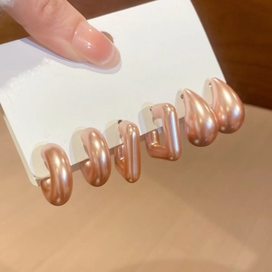 Detailed close-up of a three-piece gold geometric stud earring set held on a display card