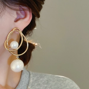 Gros plan d'un mannequin portant des boucles d'oreilles perles dorées, vue latérale douce