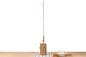 Detailed shot of a woven cylindrical bag with a golden chain on a wooden table setup