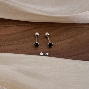 Minimalist silver screw-back earrings with 4mm black zircon on a walnut wood surface