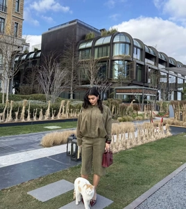 Outdoor street style shot of army green faux suede two-piece set with a matching white cat