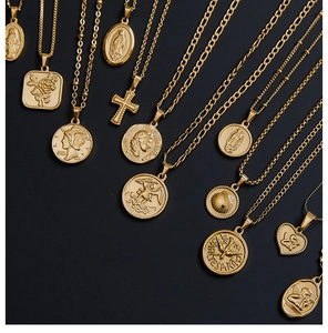 Flat lay of multiple 18K gold-plated titanium steel pendants with vintage icons on black
