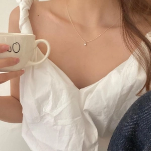 Minimalist gold necklace with a teardrop zircon pendant worn by a model in a casual setting