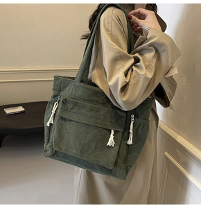 Sac cabas en velours côtelé vert foncé avec texture fine et décor de glands blancs