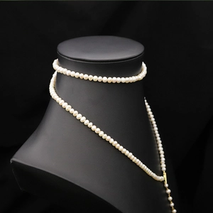 Detailed close-up of natural white pearls and gold metal connector on a luxury necklace