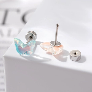 Boucles d'oreilles papillon en titane irisé bleu et rose sur un piédestal blanc épuré