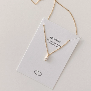 Close-up of a marquise-cut zircon pendant on a delicate gold chain displayed on a card