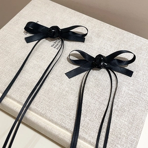 Close-up of a pair of black satin ribbon hair clips with delicate rose ornaments