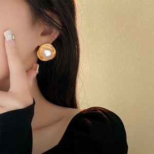 Gros plan de boucles d'oreilles vintage en spirale dorée avec perles blanches sur oreille