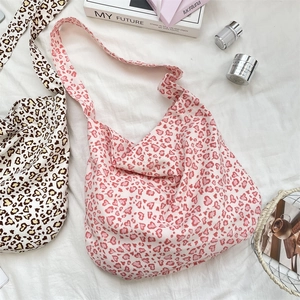 Flat lay of pink and brown leopard heart print canvas tote bags on white fabric