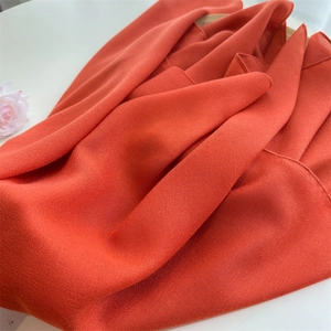 Detail of soft orange linen scarf fabric showing natural texture and vibrant solid color