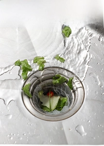 Close-up of disposable mesh strainer filtering food waste in a stainless steel kitchen sink