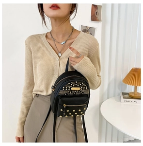 Detail of a black PU leather mini backpack featuring gold studs and zip pocket styling