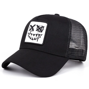 Black mesh trucker hat featuring a white graffiti-style face embroidery and curved brim