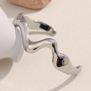 Macro detail of silver wavy open bangle showing high-polished metallic finish and sleek design