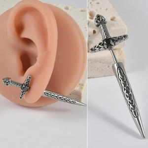 Macro detail of sword earring with black zircon inlay and Celtic patterns on a stone base