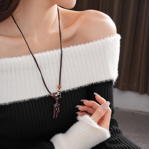 Detail of a brown bear pendant necklace on a model wearing a black and white plush top
