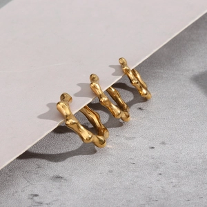 Close-up of gold stainless steel stud earrings with irregular rivet texture on card