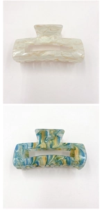 Detail of rectangular marble-pattern acrylic hair claws in pearly white and teal colors